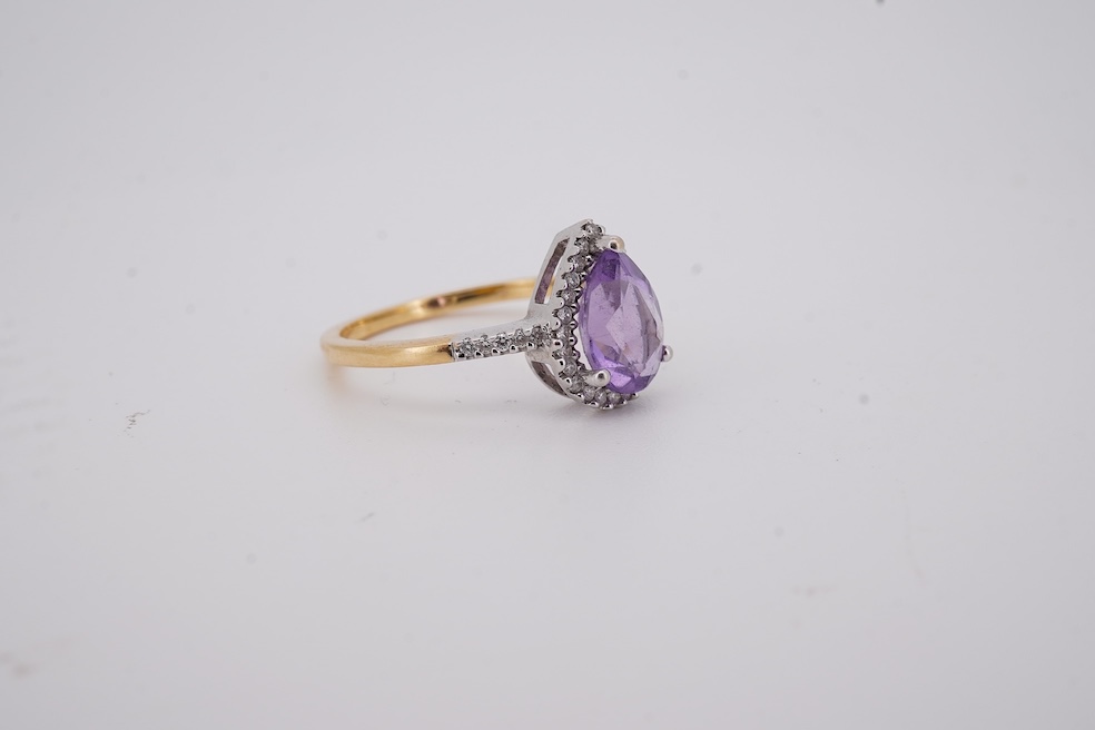 A modern 18ct gold and single stone pear cut amethyst set ring, with diamond chip set border and shoulders, size O, gross weight 3.4 grams. Condition - fair to good